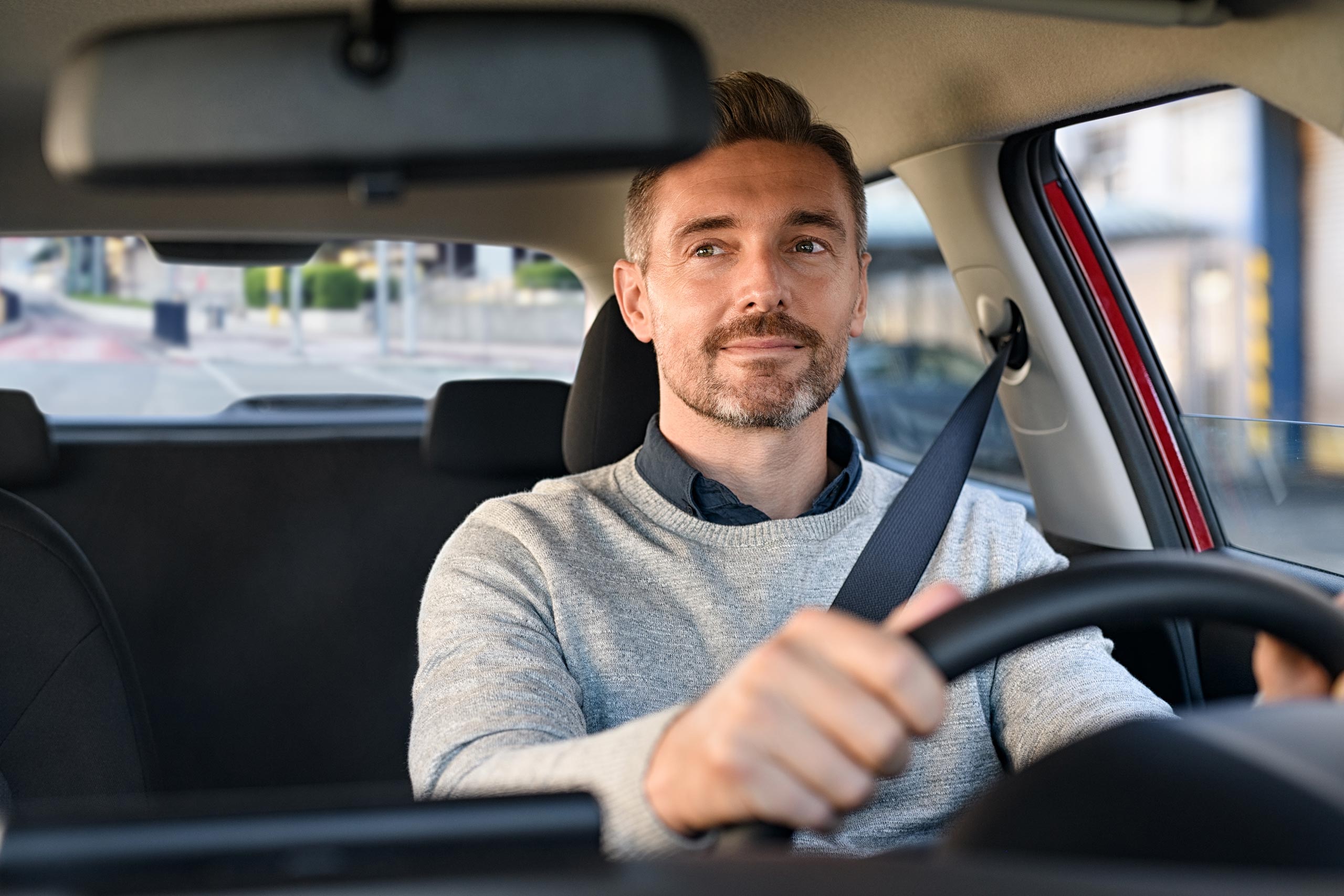 Handsome middle aged man with short facial hair driving a car