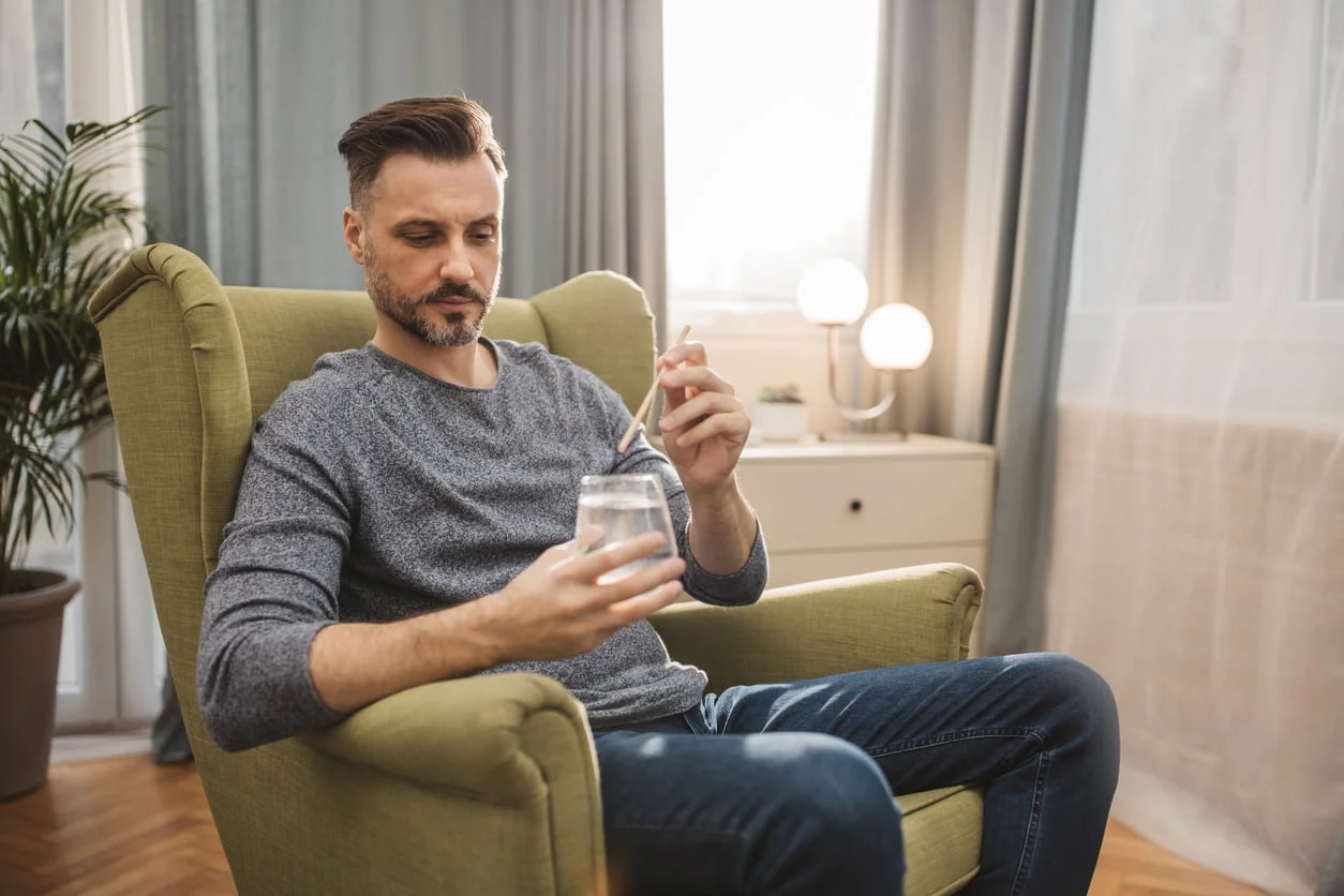 Man holding a glass of water with a straw